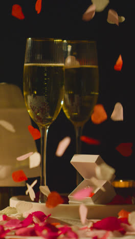 Vertical-Video-Of-Table-Set-For-Romantic-Marriage-Proposal-With-Confetti-Champagne-And-Engagement-Ring-1